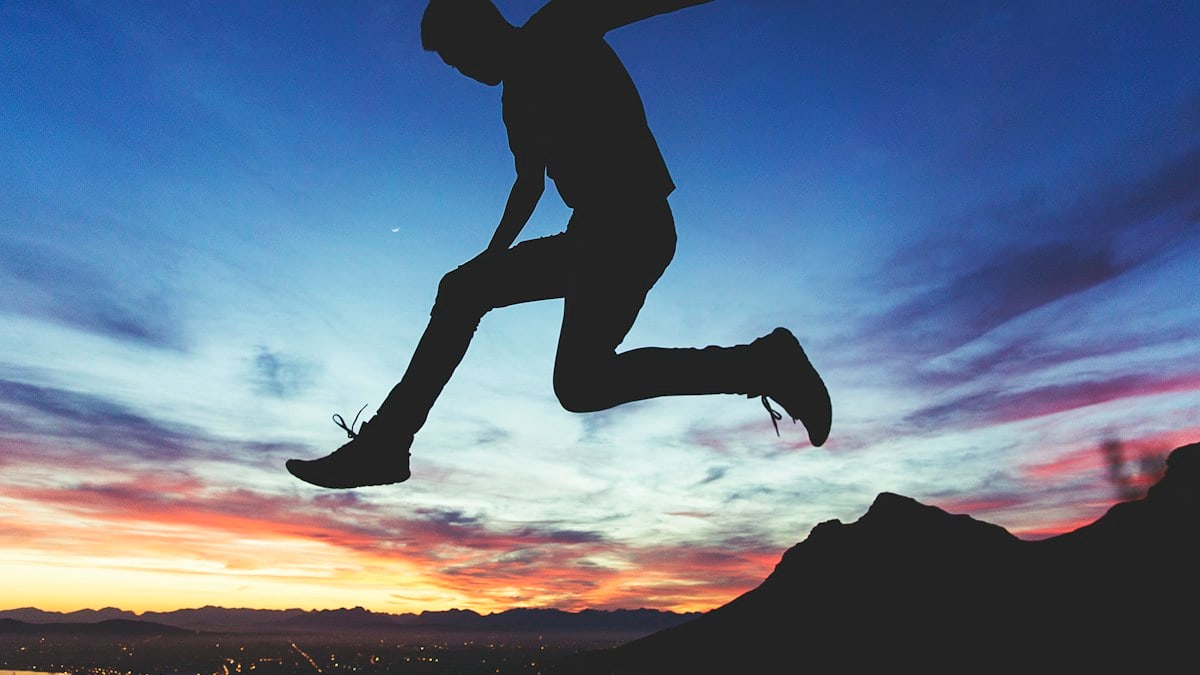 silhouette of man jumping near mountain